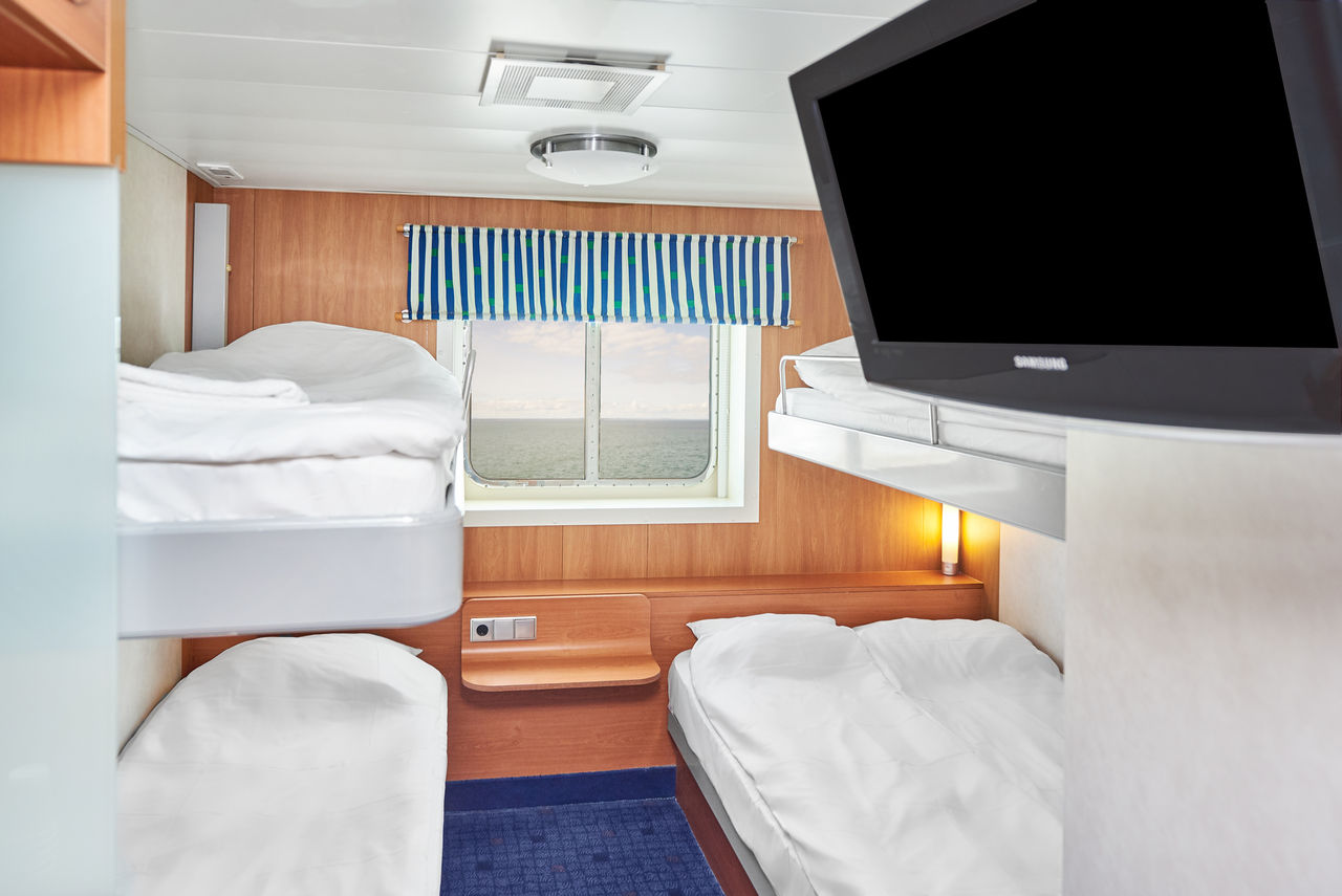 a brightly lit 4 berth cabin (2 sets of bunk beds) with TV and a window.